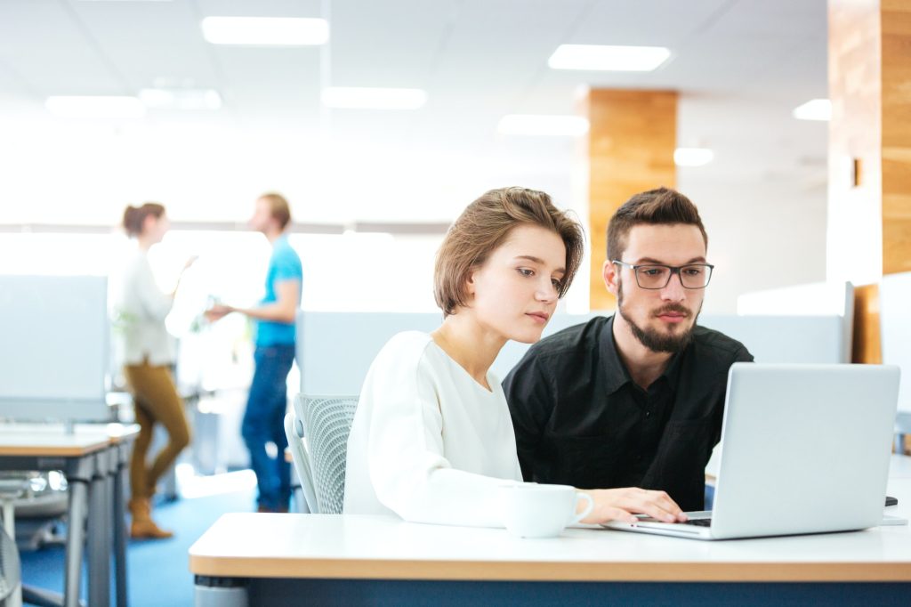 Serious focused man and woman working with laptop in office